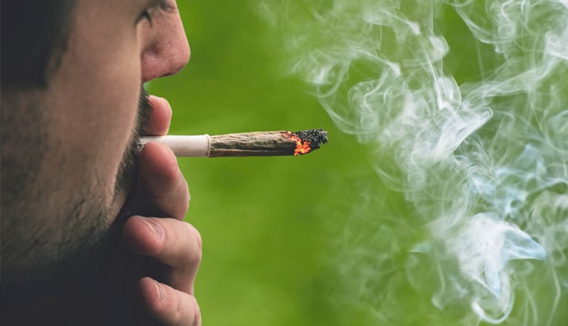 Homme fumant un joint de cannabis