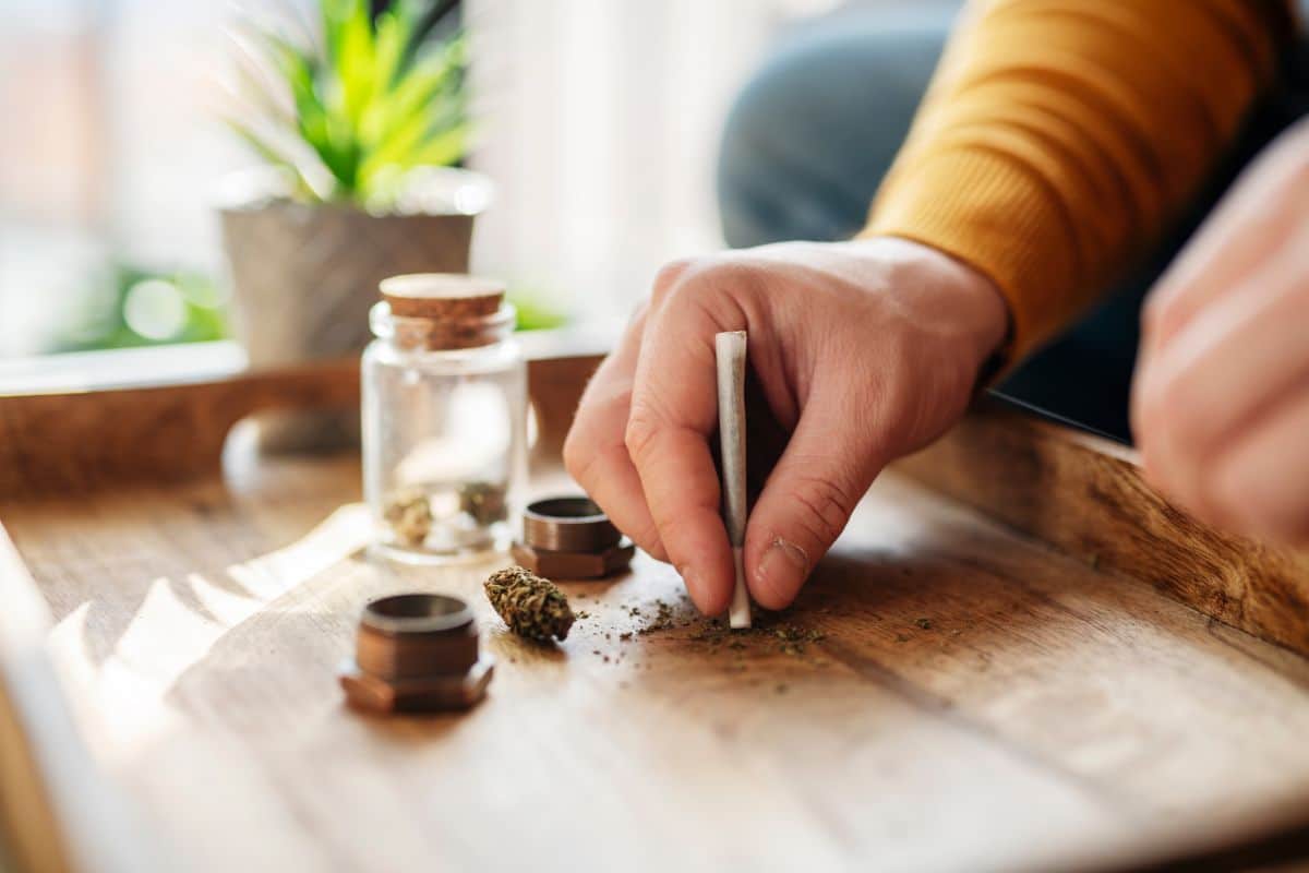 Main préparant un joint sur une table en bois