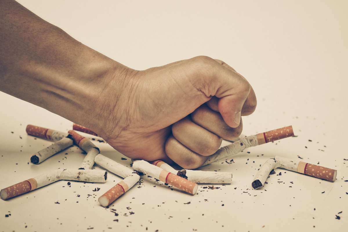Main écrasant des cigarettes sur une table après avoir arrêté de fumer