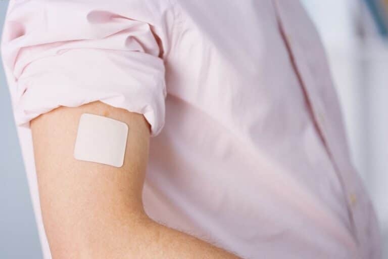 Gros plan sur un patch nicotine placé sur le bras d'un droit d'un homme en chemise rose