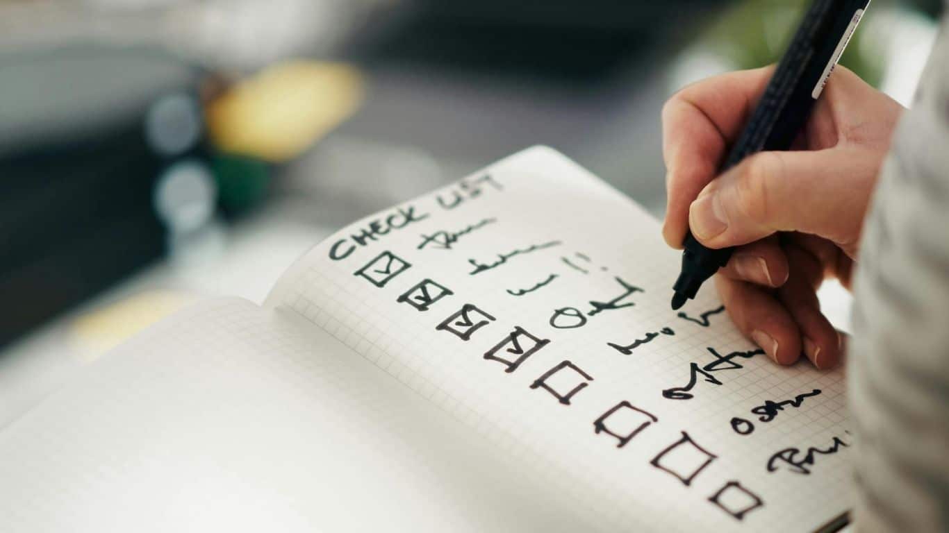 Personne cochant une check-list dans un carnet, symbole de la preparation de son arret du tabac