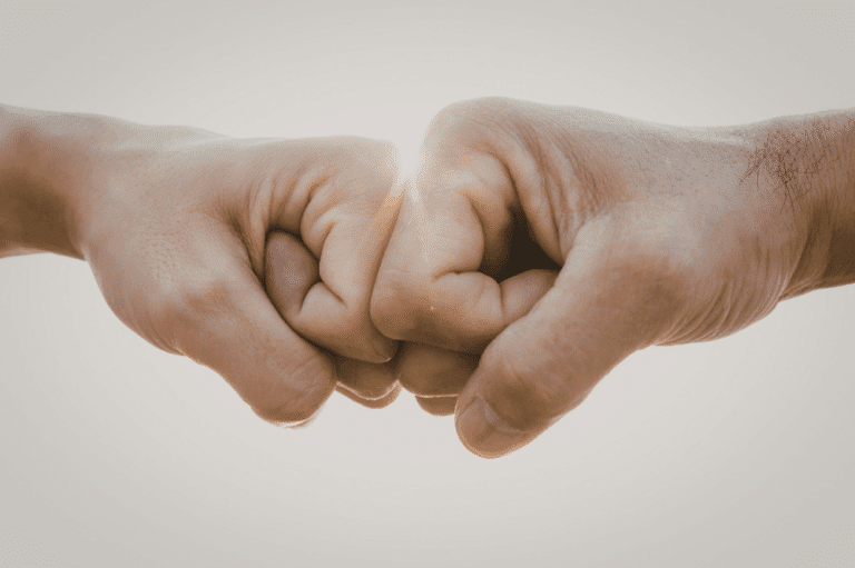 Deux mains se font un check du poing pour symboliser l'aide d'un proche pour arrêter de fumer