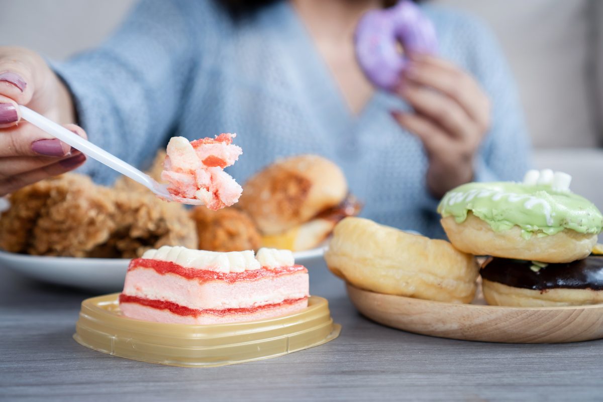 Femme attablée devant des gâteaux et des beignets