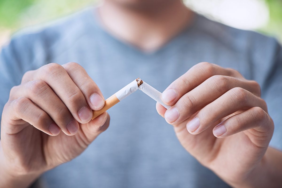 Homme brisant une cigarette en deux pour arrêter de fumer