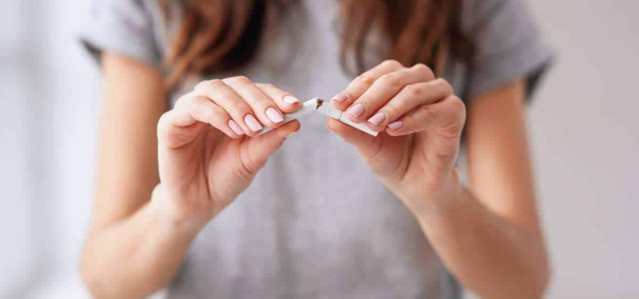 RESET-arreter-de-fumer-du-jour-au-lendemain Femme au long cheveux bruns montrant son envie d'arrêter de fumer du jour au lendemain en rompant une cigarette