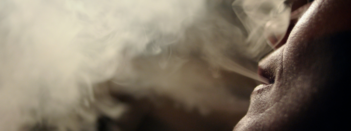 Gros plan de profil de la bouche et du menton d'une personne en train de recracher un nuage de fumée de cigarette