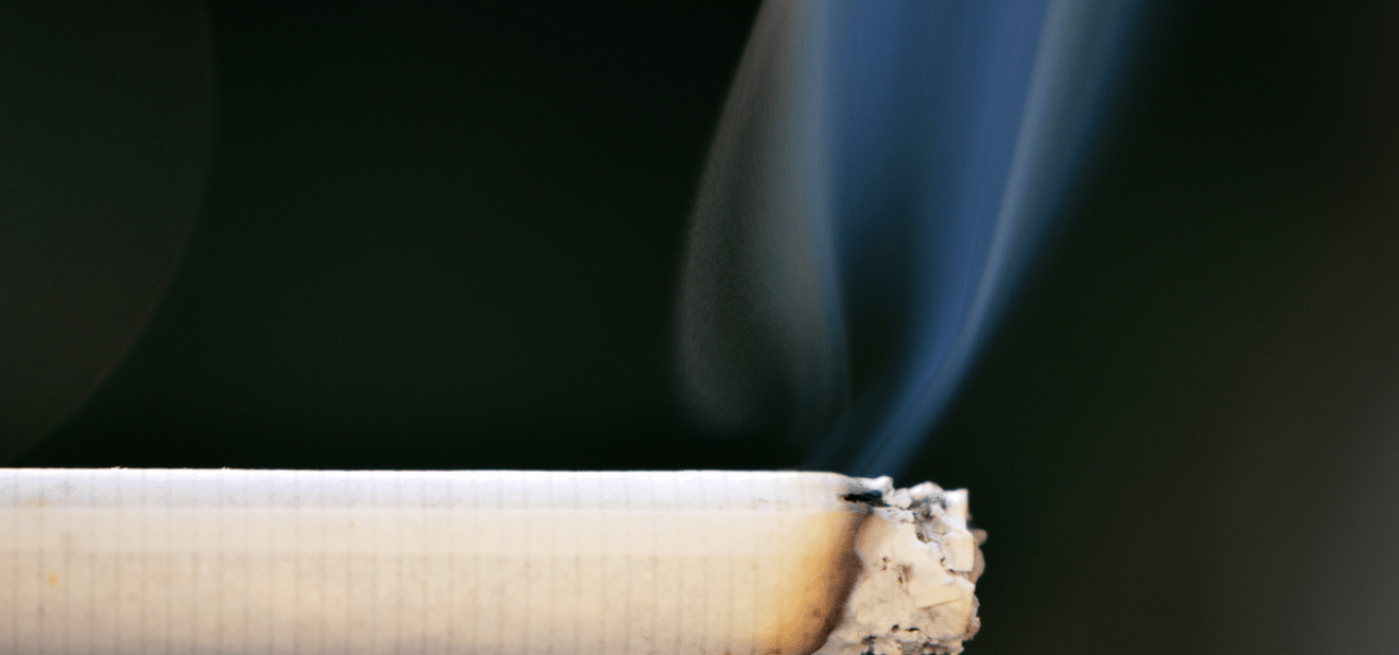 RESET-blog-fumee-danger Gros plan sur une cigarette allumée, en train de se consumer et de produire de la fumée nocive pour la santé