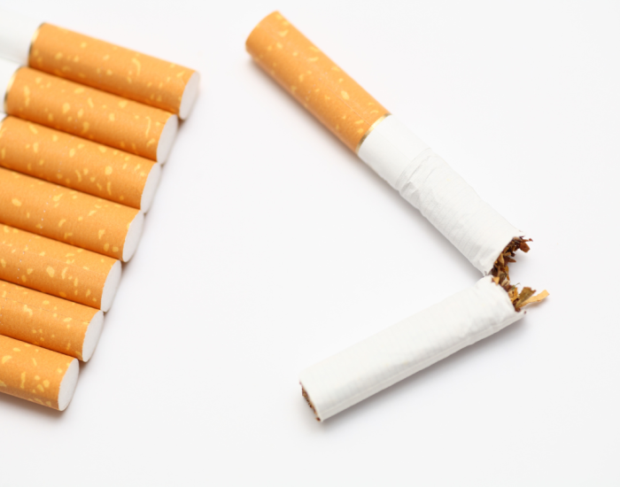 Cigarettes alignées à côté d'une cigarette coupée en deux afin d'illuster le fait d'arrêter de fumer