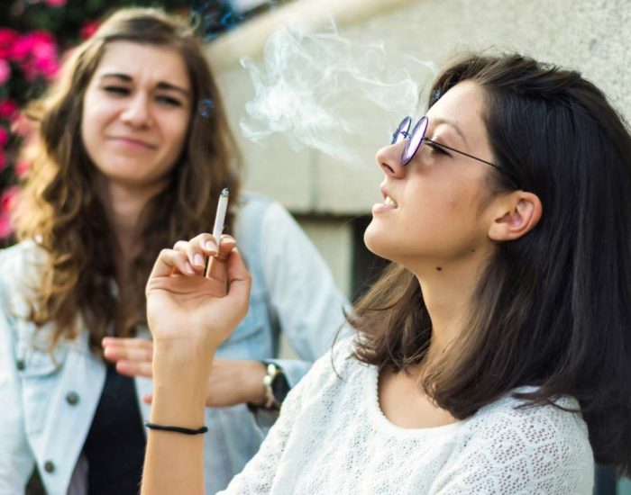 Deux jeunes filles dont une incommodée par la fumée de cigarette de l'autre
