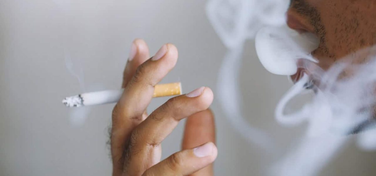 Homme qui crapote une cigarette avec de la fumée qui se propage