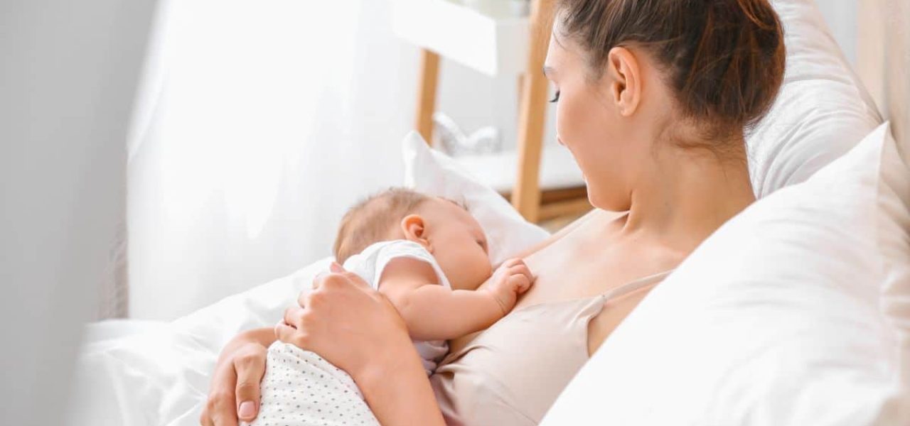 Femme couchée dans un lit allaitant sur nouveau né