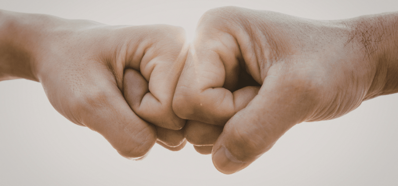 Deux mains se font un check du poing pour symboliser l'aide d'un proche pour arrêter de fumer